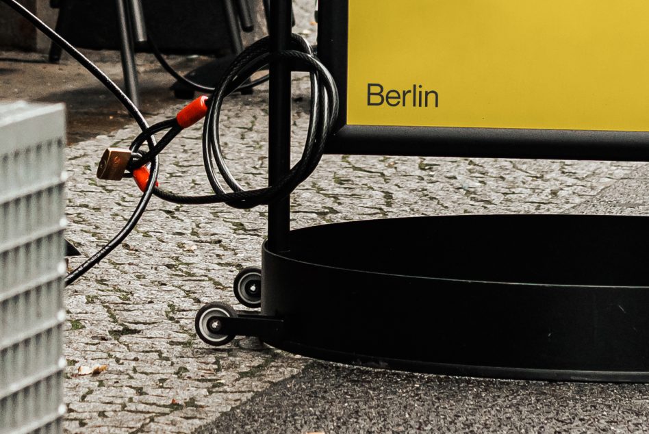 Urban outdoor signage mockup featuring a locked bike and yellow sign with 'Berlin' text, ideal for city branding projects.